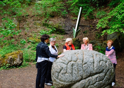 Erwachsene berühren große Gehirn Statue aus Stein beim Outdoor Kunstweg