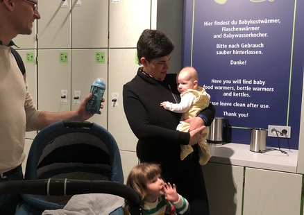 Eltern mit Kind auf dem Arm an der Babybar mit Wasserkocher im Untergeschoss