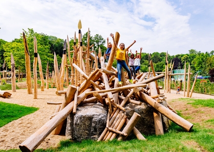 Kinder auf Steinzeitspielplatz Holzkonstruktion in Outdoor Familien Erlebniswelt