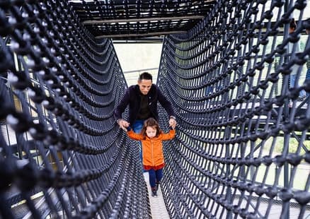 Kind und Vater klettten durch den Klettertunnel auf dem Erlebnisturm
