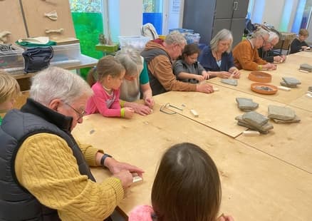 Großeltern und Kinder basteln ein Steinzeitmesser