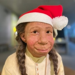 Kina das Neanderthalerkind trägt Weihnachtsmütze