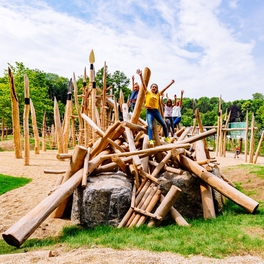 Kinder auf Steinzeitspielplatz Holzkonstruktion in Outdoor Familien Erlebniswelt