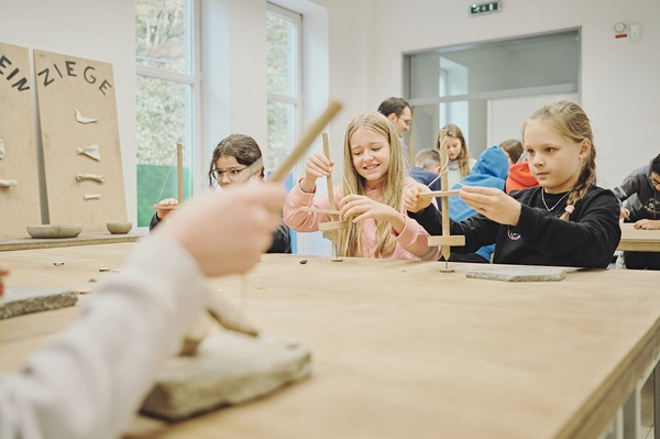 Kinder erstellen Steinzeitamulett bei Workshop für Schulen