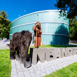 Neanderthaler MR N und Tinka stehen beim Neandertal Schriftzug vor Museum