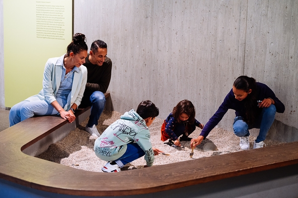 Familie gräbt Knochen im Sandkasten in Ausstellung aus
