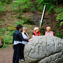 Erwachsene berühren große Gehirn Statue aus Stein beim Outdoor Kunstweg