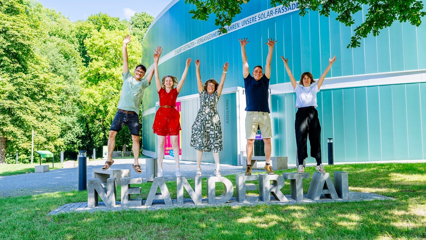 Erwachsene stehen auf dem Schriftzug vor dem Museum