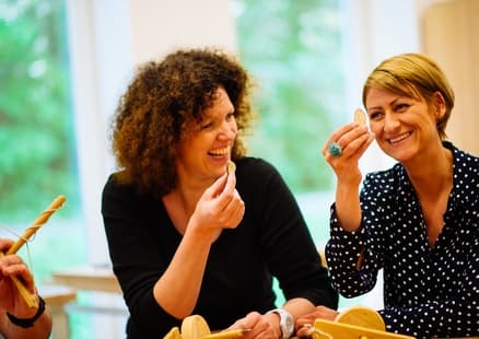 Erwachsene zeigen durch Steinzeitbohrer gemachtes Loch bei Lehrerfortbildung