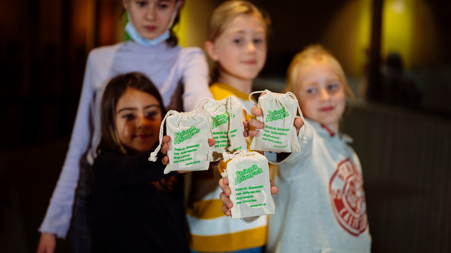 Kinder präsentieren Beutel aus Steinzeit Action Pack