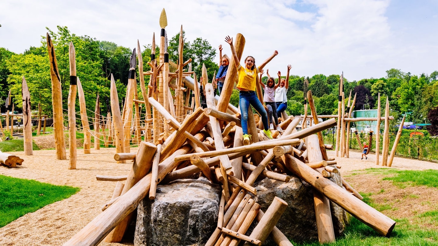 Kinder auf Steinzeitspielplatz Holzkonstruktion in Outdoor Familien Erlebniswelt