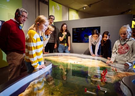 Familie lauscht Führung an Afrika-Karte in Ausstellung