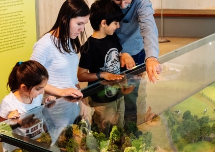 Familie betrachtet Miniatur Grabungsstation in Ausstellung
