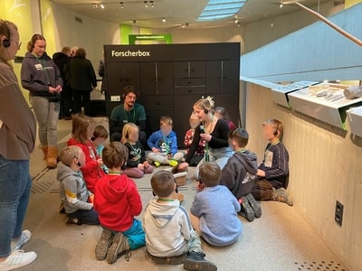 Kinder sitzen im Museum auf dem Boden im Rahmen einer Führung