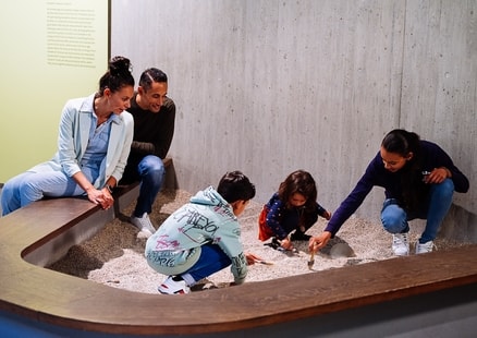 Familie gräbt Knochen im Sandkasten in Ausstellung aus