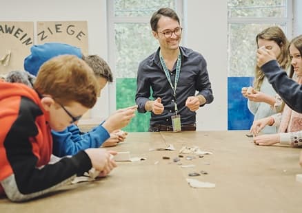 Kinder stellen Steinzeitmesser im Workshop für Schulen her