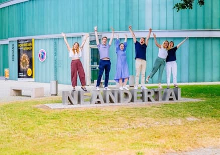 Erwachsene posieren auf Neandertal Schriftzug bei Firmen und Teamevent