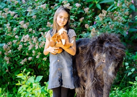 Kind mit Mammut Kuscheltier steht neben Baby Mammut Tinka