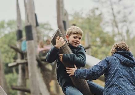 Schulklasse spielt auf Holz Speernachbauten beim Steinzeitspielplatz